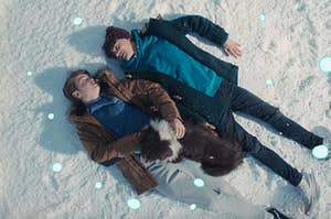Charlie and Nick from Heartstopper lying in the snow next to each other and staring into each other's eyes