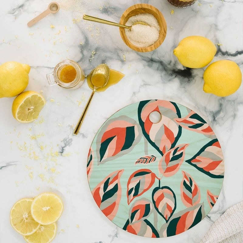 a leaf patterned cutting board on a countertop with sliced lemons