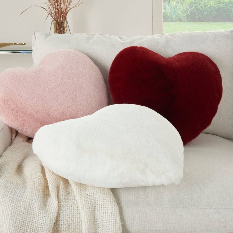 Pink, white, and burgundy heart-shaped pillows adorning a cream-colored sofa