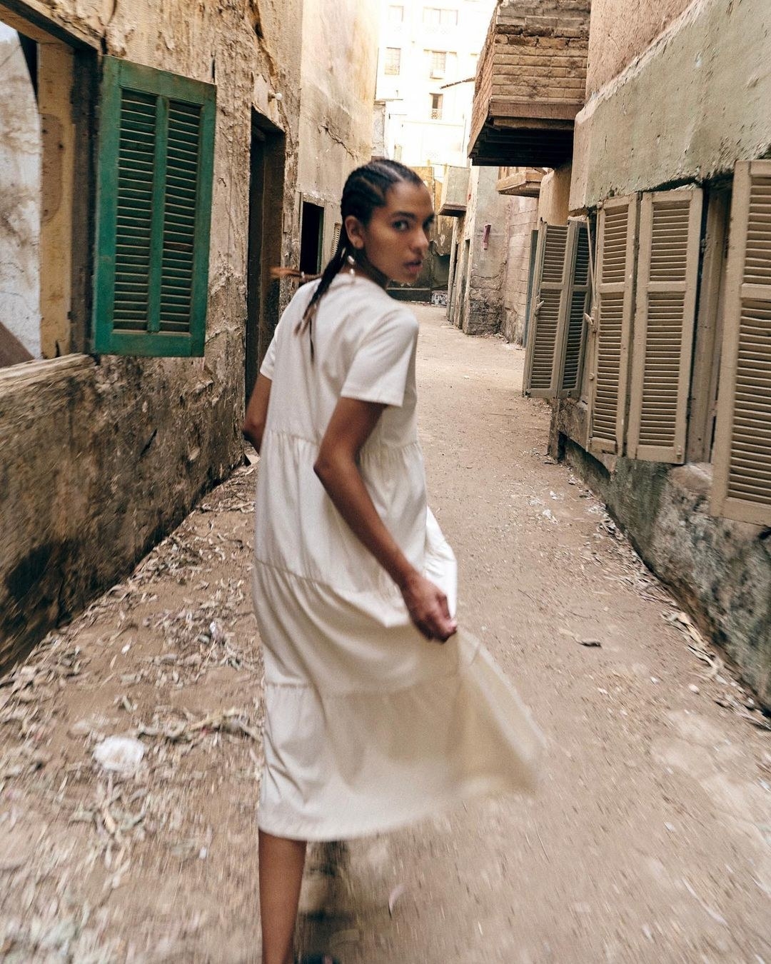 A person wearing the mid-length tiered dress while walking through a narrow alleyway