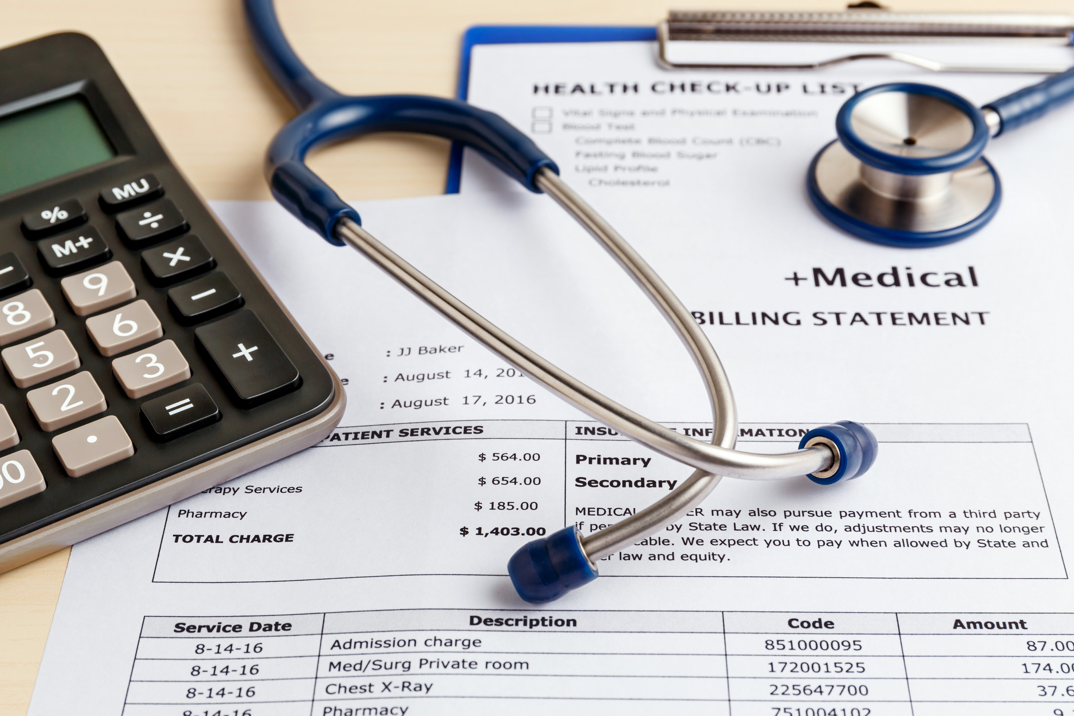 A medical billing statement with a calculator and stethoscope on top