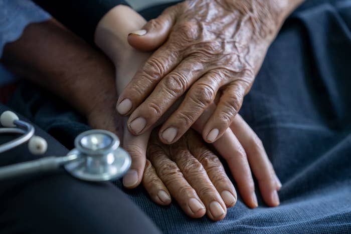 A close up of two people holding hands on a hospital bed