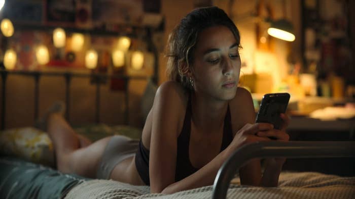 A girl texts on her phone while lying on her bed