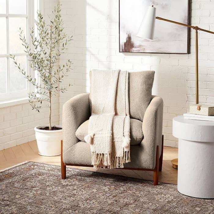An image of an accent chair with an all-over Sherpa finish and wooden legs