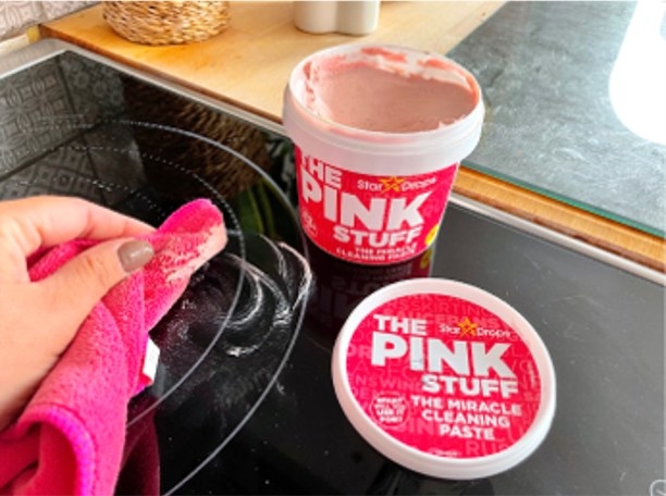 A person uses The Pink Stuff on a stovetop