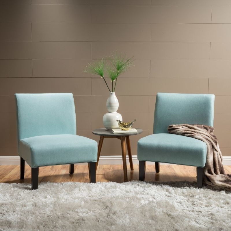An image of two light blue accent chairs with rubber wood legs