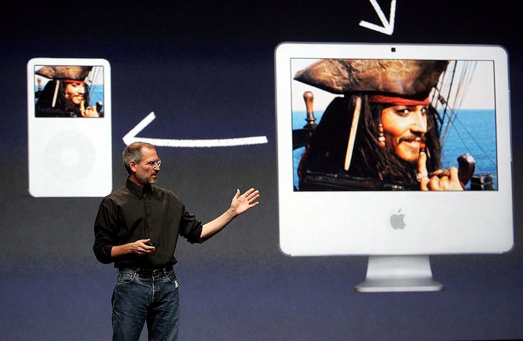 Steve Jobs onstage showing an image on a large Mac screen and also on an iPod