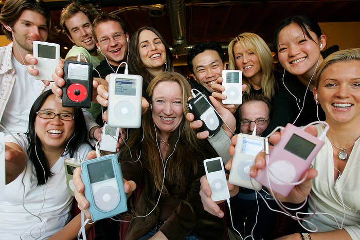 A group of smiling young people holding up their iPods attached to earbuds