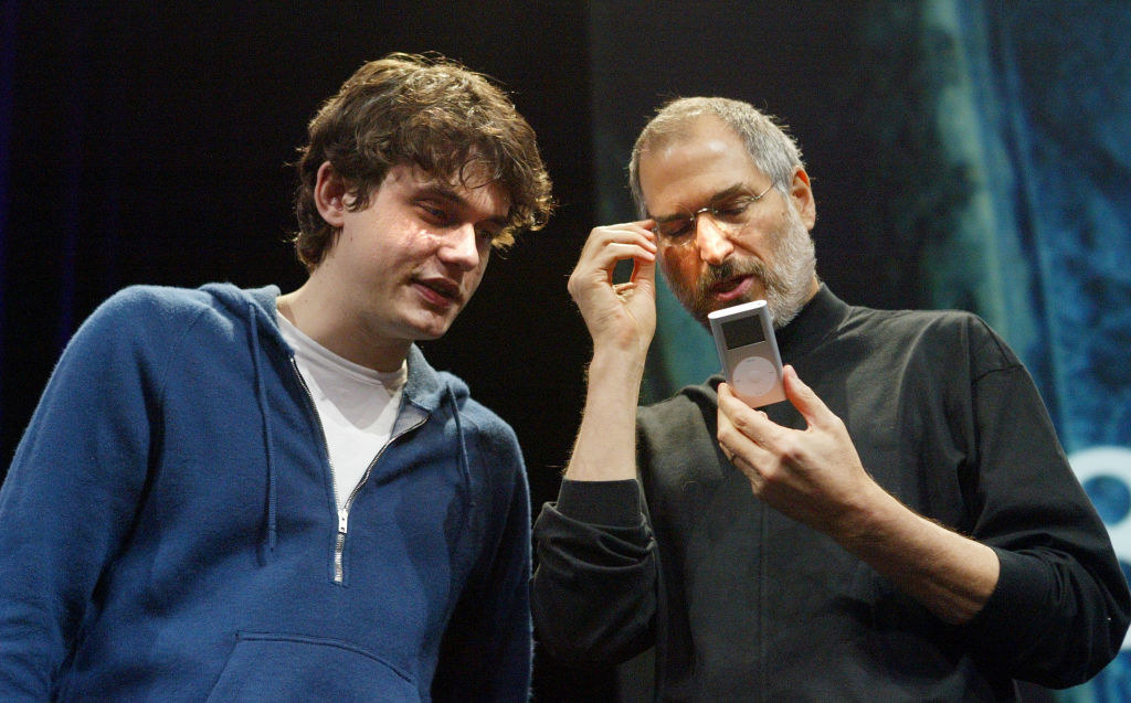 John Mayer in a hoodie standing next to Steve Jobs and looking at the iPod he&#x27;s holding