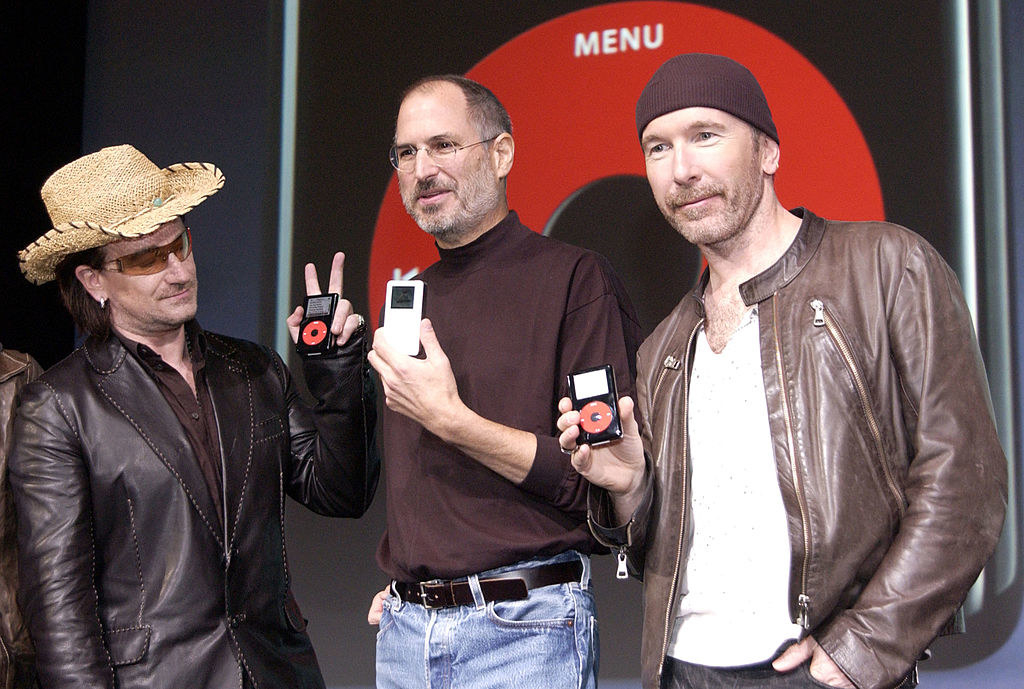 Bono and the Edge stand on either side of Steve Jobs holding up iPods