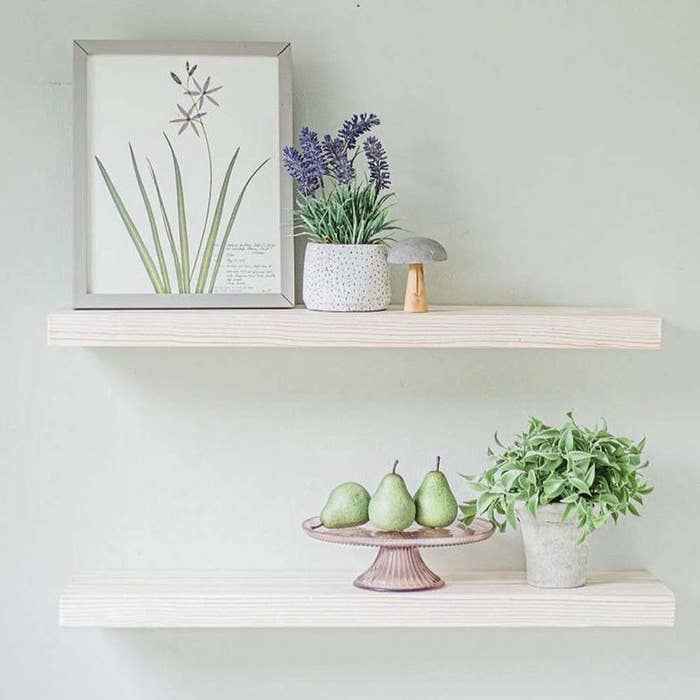 wooden floating shelves with plants, picture frames, and other decor items on them