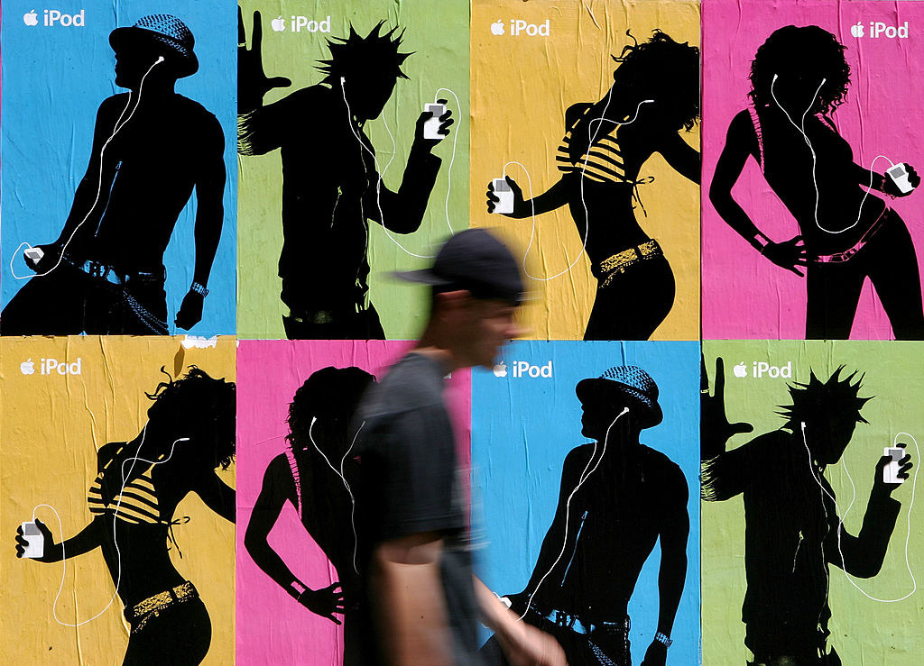 Another person walking by an ad with silhouettes of people dancing while listening to their iPods