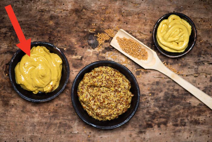 Different bowls of mustard on a table.