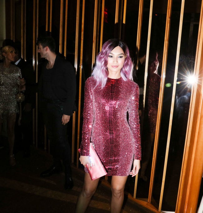 Gemma Chan in a short sequined dress and matching reddish purple hair