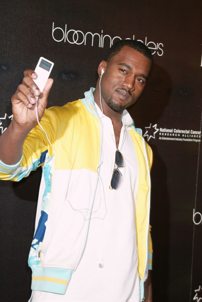 Kanye West holding up an iPod he&#x27;s listening to with earbuds