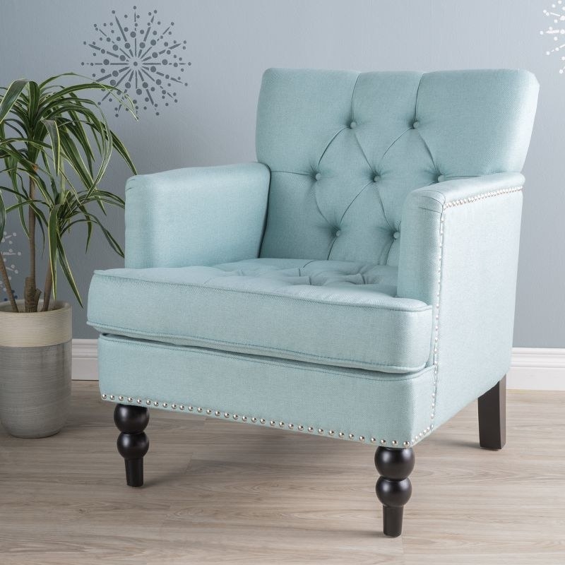 An image of a blue tufted armchair with solid birch legs