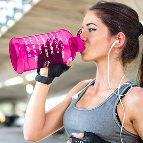 Model drinking from the pink water bottle while working out