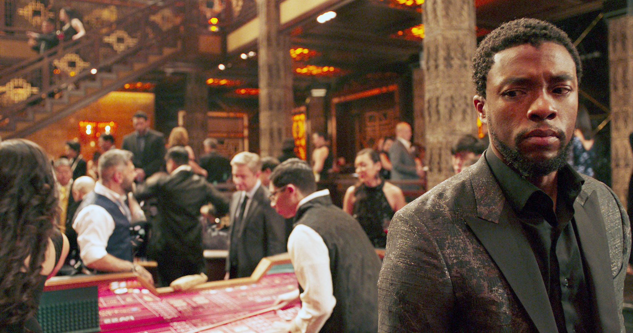Chadwick&#x27;s character stands in a casino with Martin&#x27;s character in the background