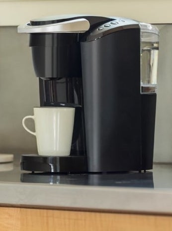 the black Keurig brewing a single cup of coffee