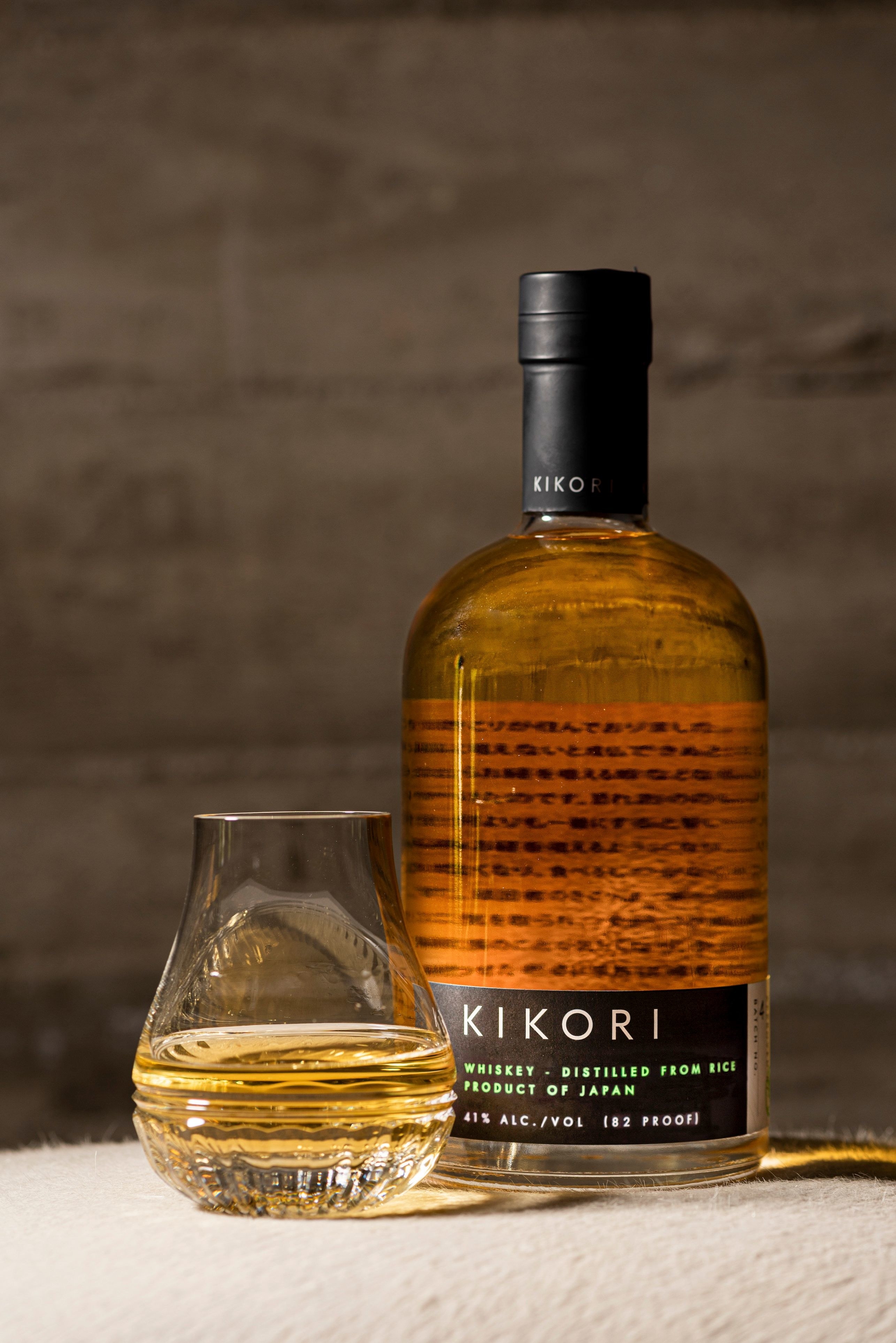 A bottle of Kikori Whiskey next to a glass containing the whiskey
