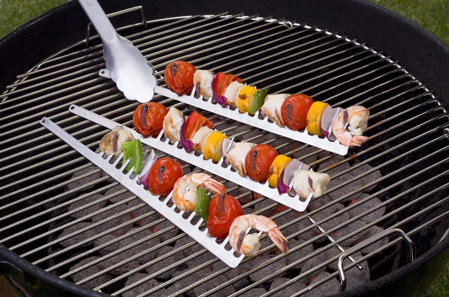 a trio of stainless steel grilling combs filled with fresh veggies and seafood