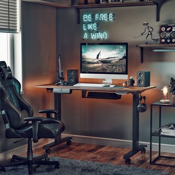 the brown wood desk at chair level with monitor and speakers