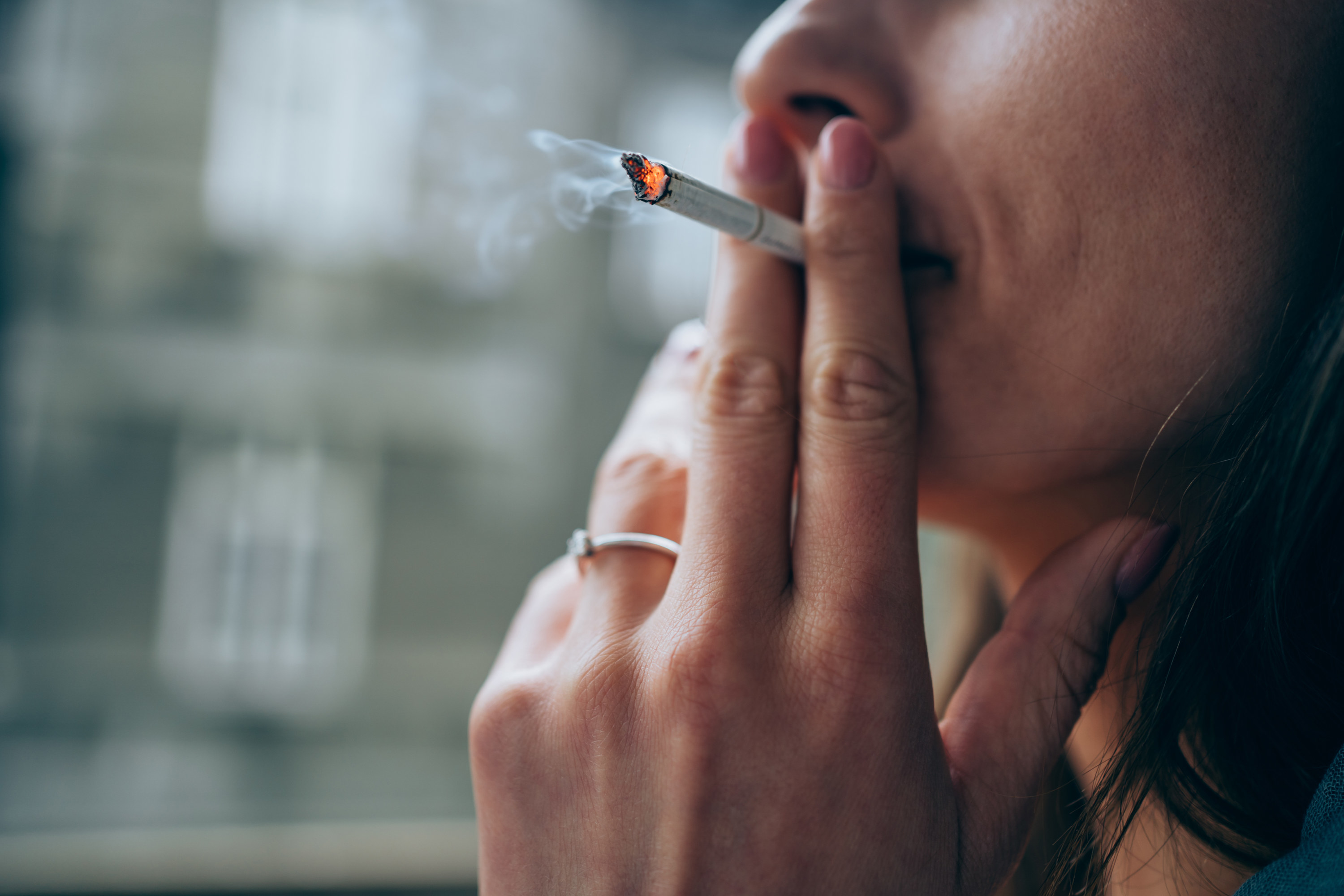 An up-close shot of a person holding a cigarette up to their mouth