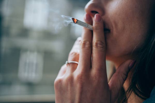 An up-close shot of a person holding a cigarette up their mouth