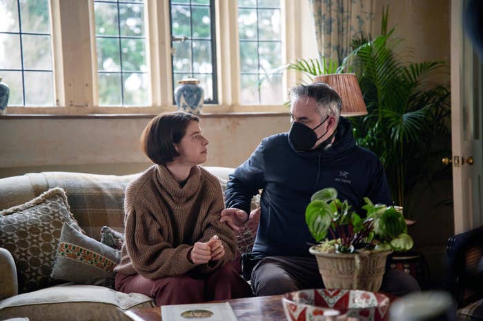 Jessie Buckley and director Alex Garland sitting on a couch together on set