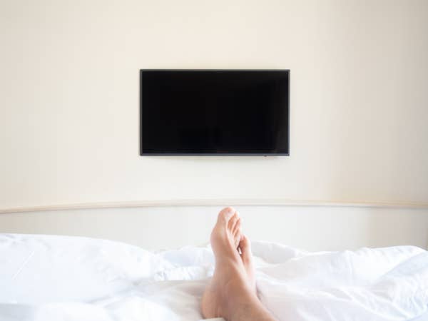 Feet laying at the foot of a bed in front of a blank TV