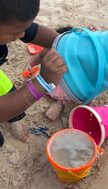 Reviewer's photo of a child playing with the collapsible pails on the beach