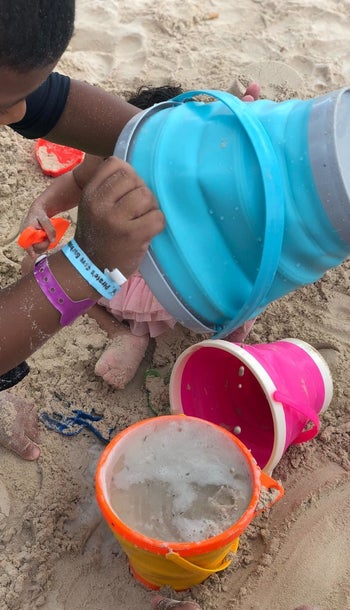 Reviewer's photo of a child playing with the collapsible pails on the beach