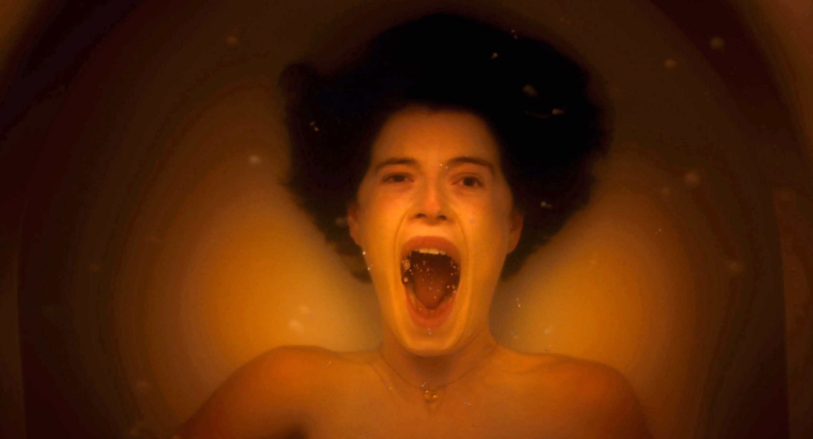 Harper lying underwater in a bathtub and screaming; her mouth is abnormally wide