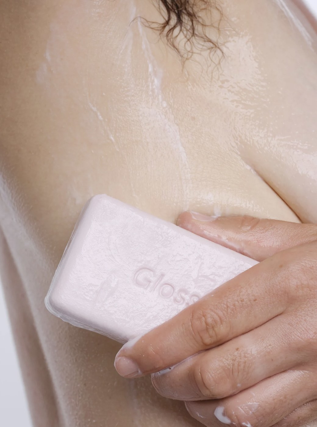 Model scrubbing the exfoliating bar into a lather on their skin