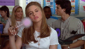 A GIF of Alicia Silverstone playing Cher Horowitz in Clueless is shown moving a fluffy pen across her face