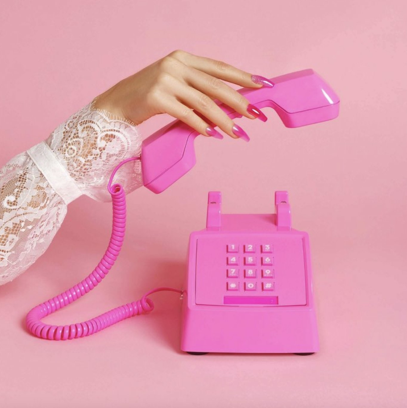 A person holding the pink telephone with a pink jelly manicure