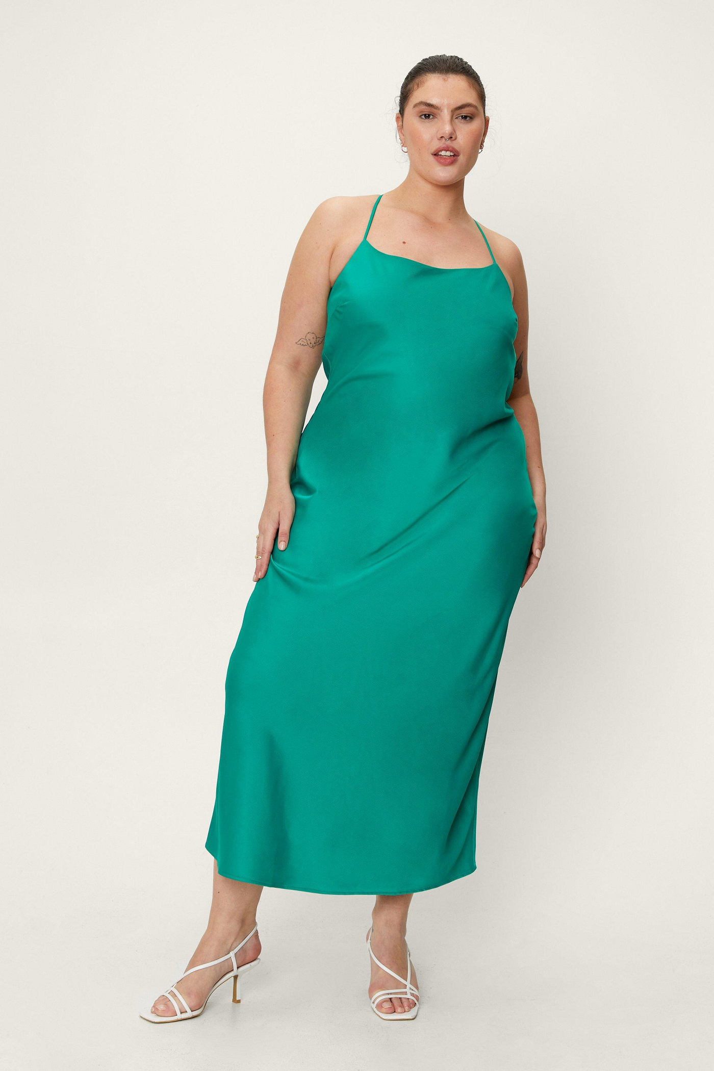 A person wearing a teal slip dress with heeled sandals