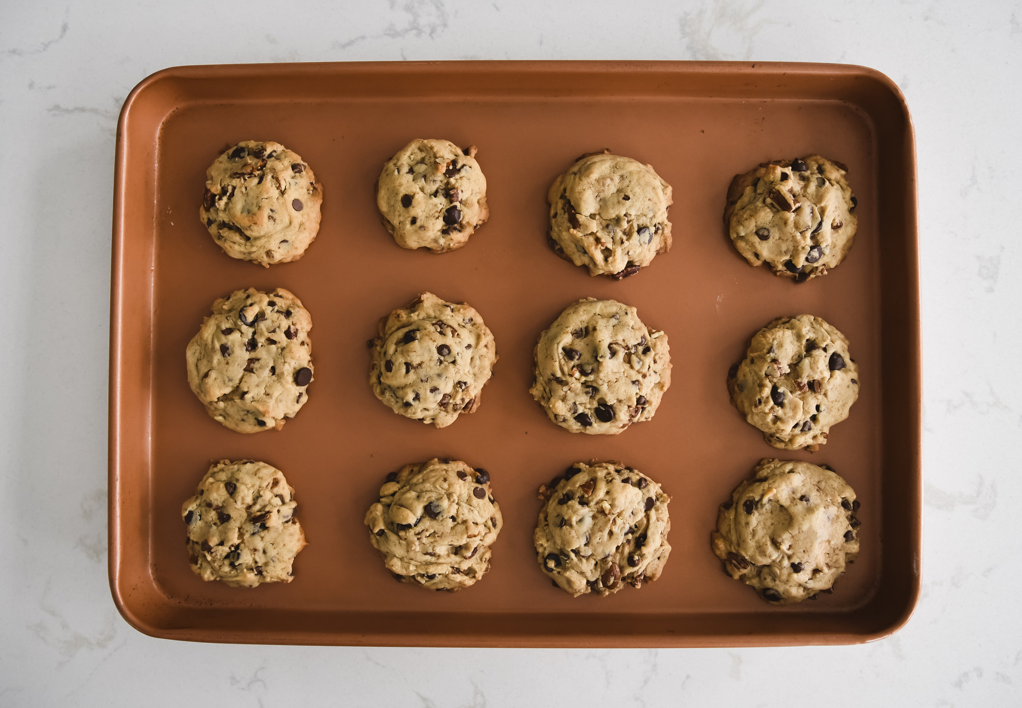 Sheet pan of freshly baked chocolate chip cookies shot from above