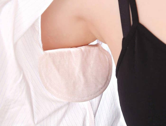 A person showing the sweat pads on the inside of their shirt