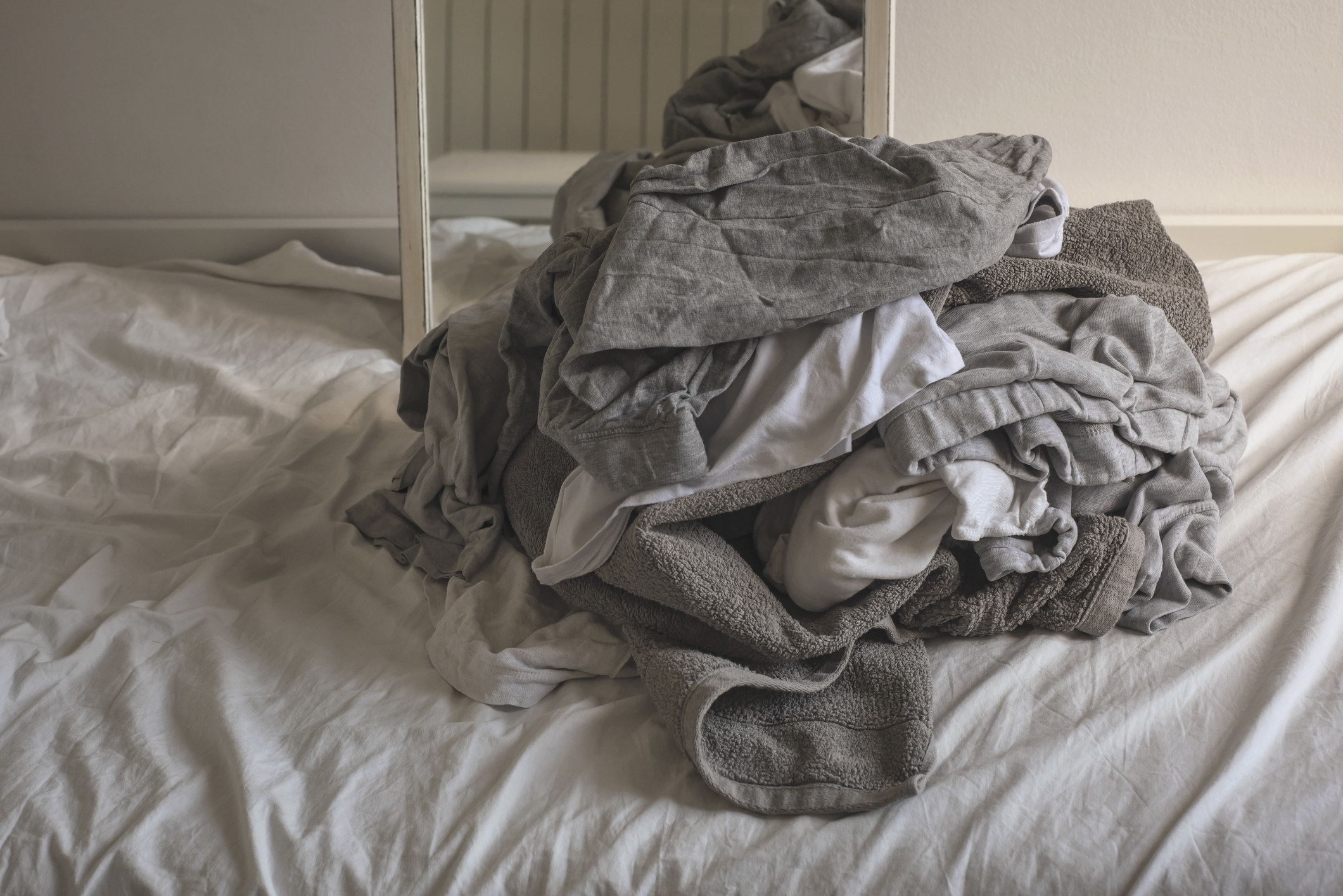 A bed with dirty, crumpled laundry on it