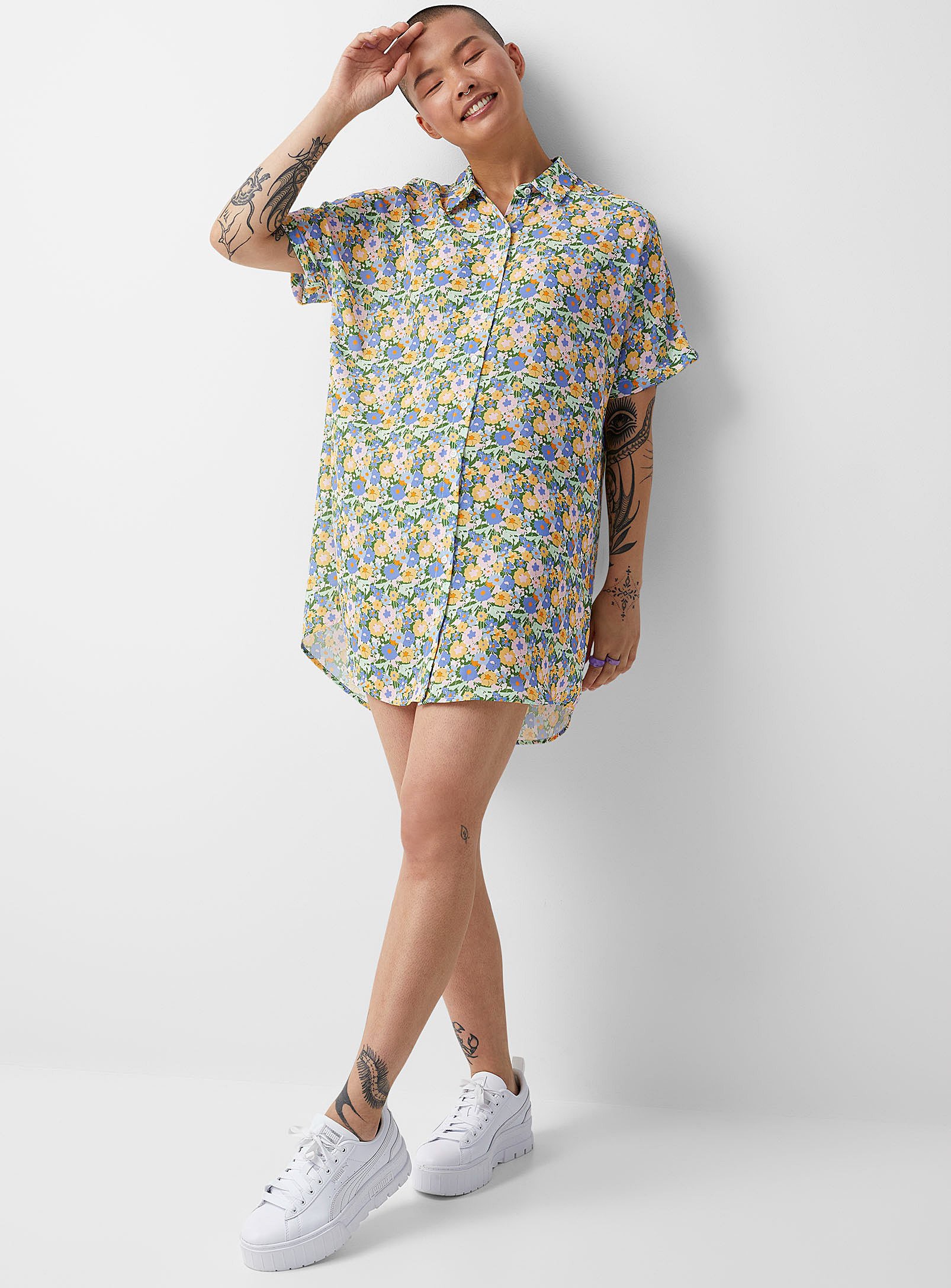 A person wearing a shirtdress with sneakers