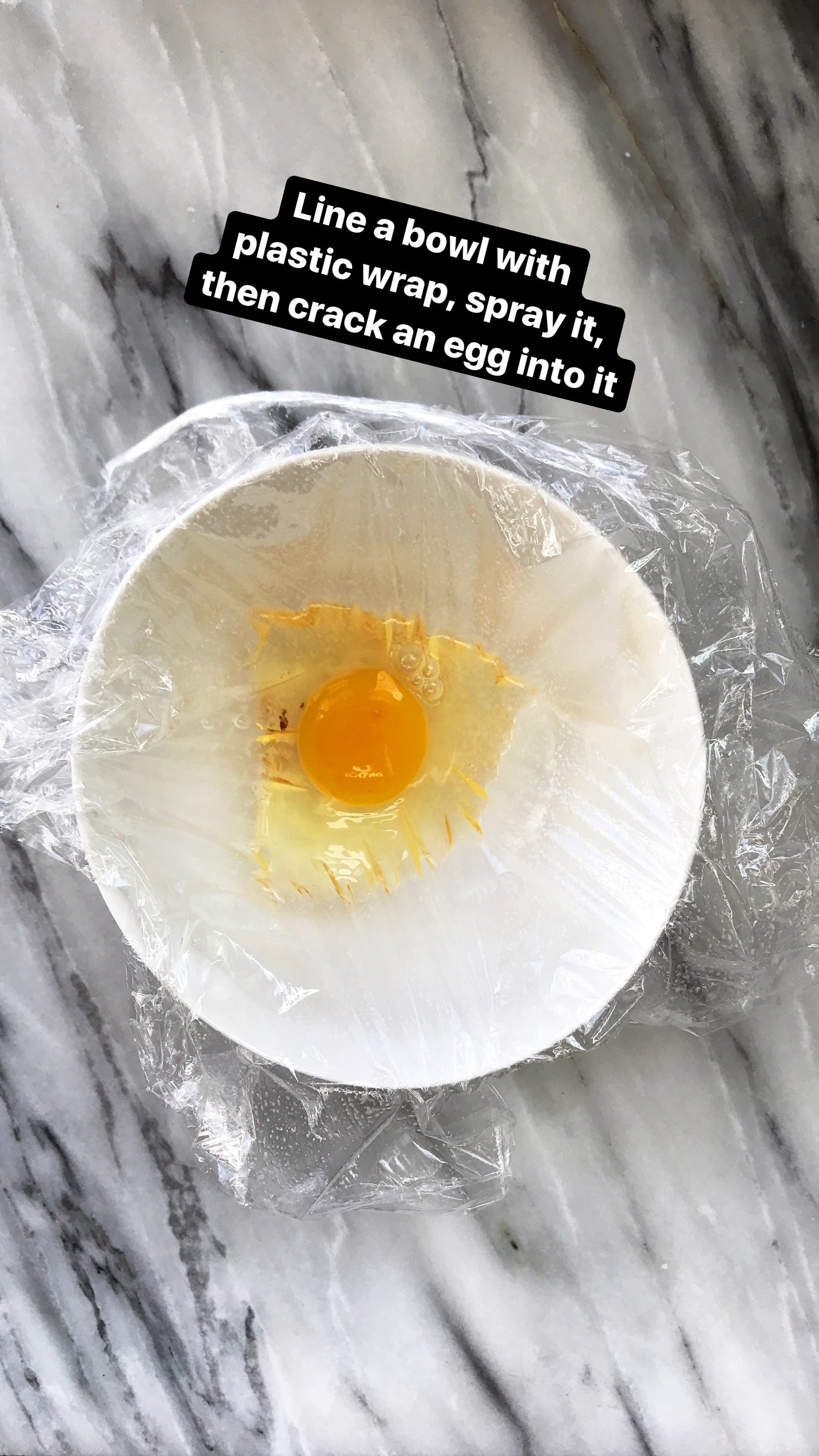 An egg in a bowl lined with plastic wrap