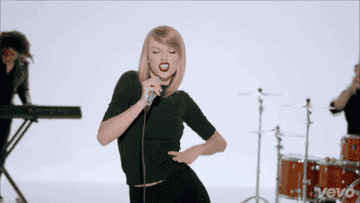 A gif of Taylor Swift in red lipstick dancing with a microphone