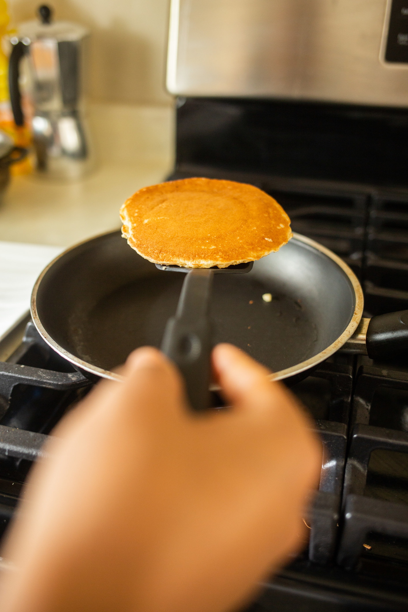 A person taking a pancake out of a pan