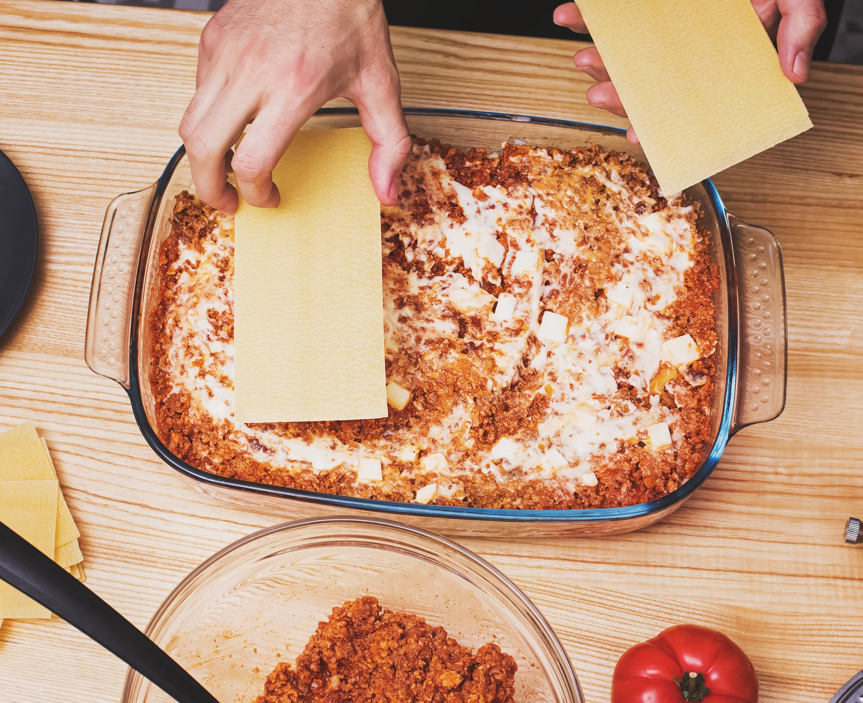 Person making lasagna in a baking dish