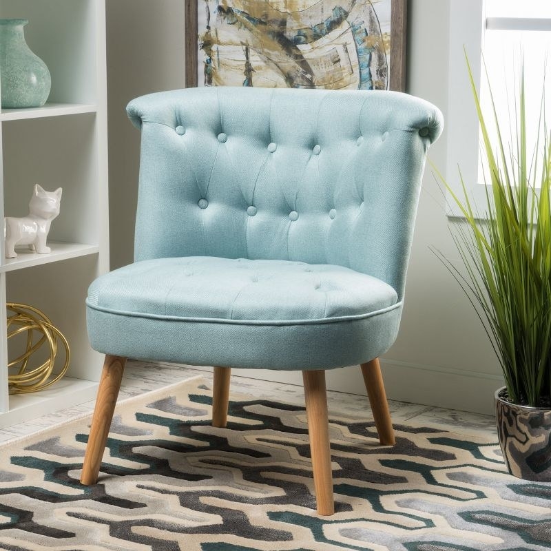 An image of a blue round tufted accent chair with a natural stain leg finish