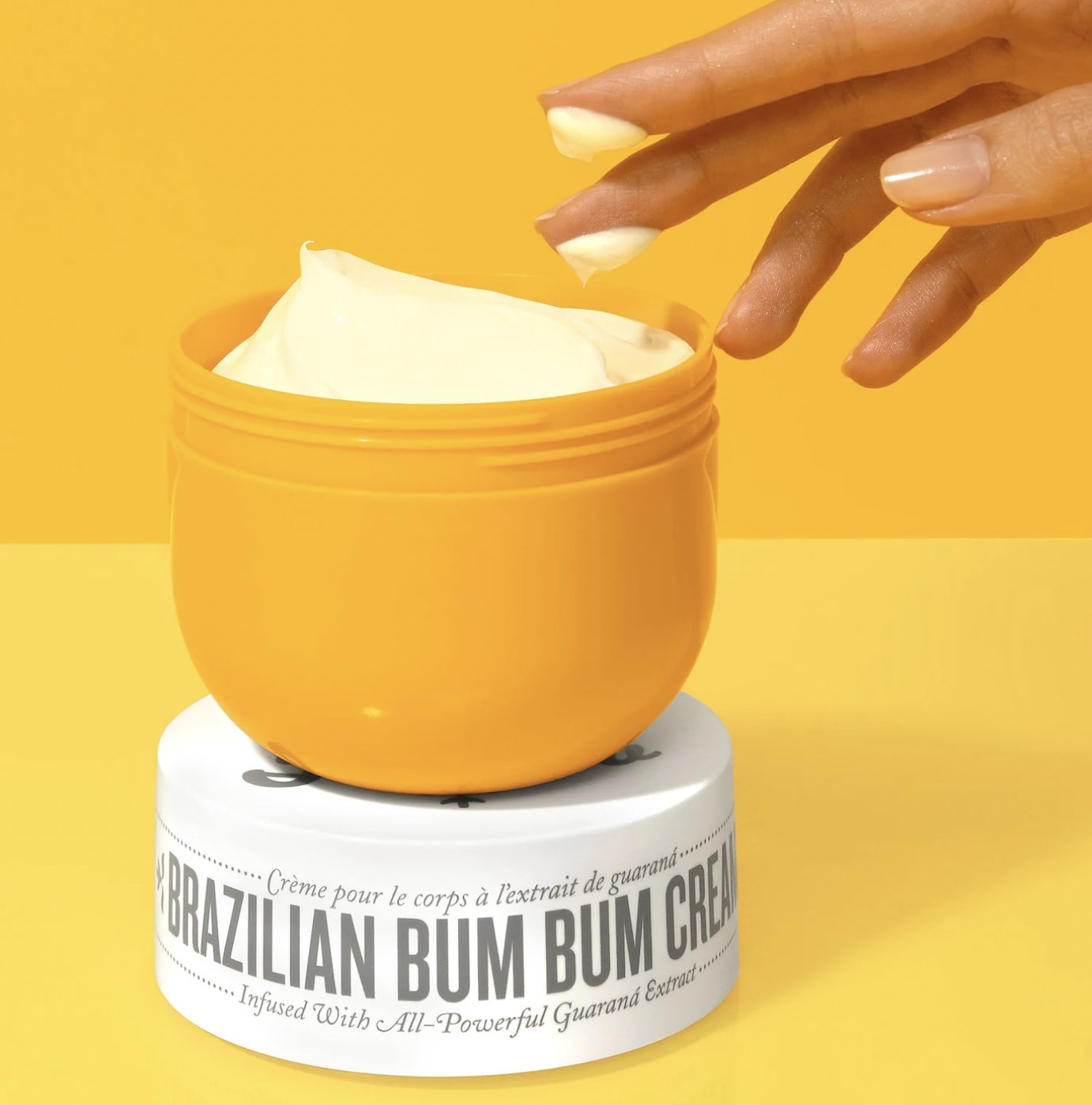 the bum bum cream jar open with someone scooping some out onto their fingertips