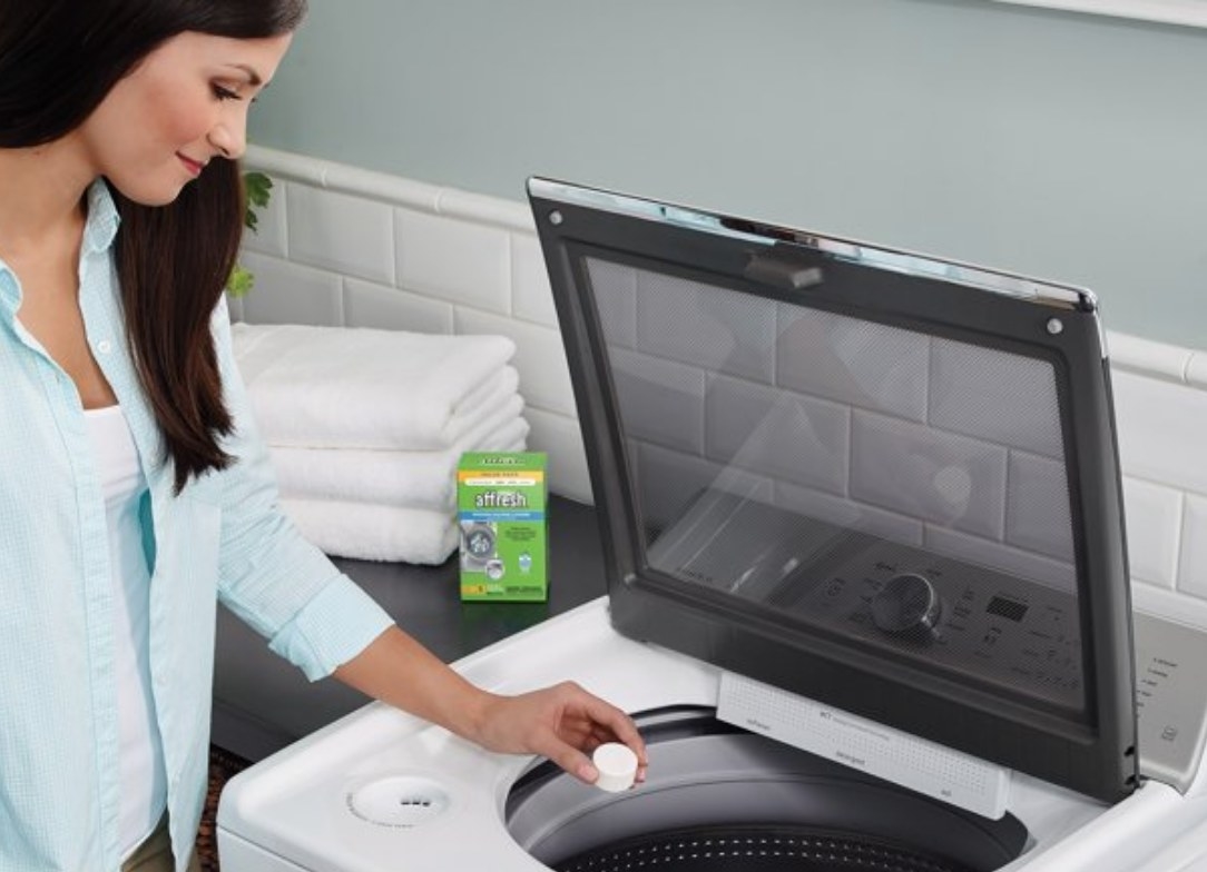 A model placing a washing machine tablet in the machine