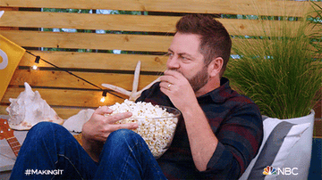 A man sitting and eating popcorn on a couch