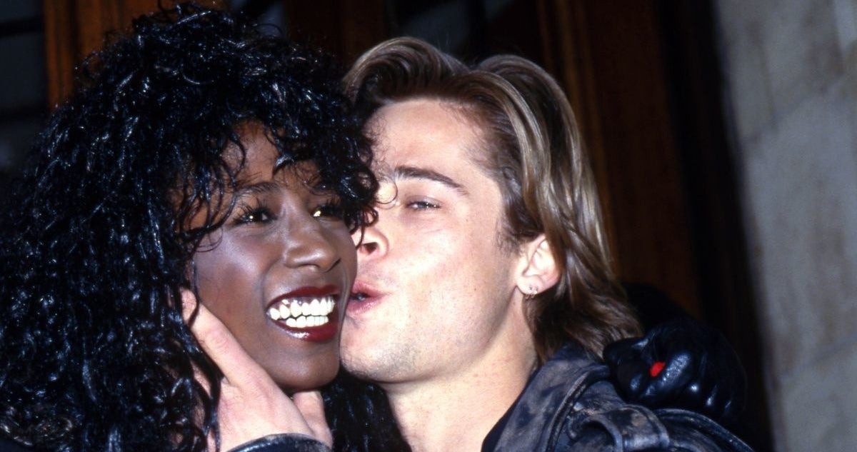 Brad Pitt kissing Sinitta on the cheek while she smiles happily